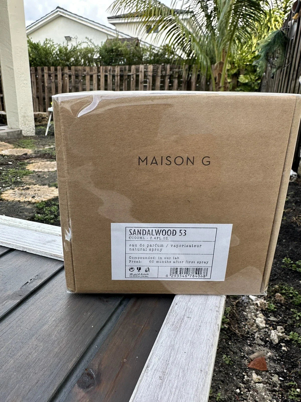 Cardboard box with 'Maison G' branding on a wooden surface outdoors.