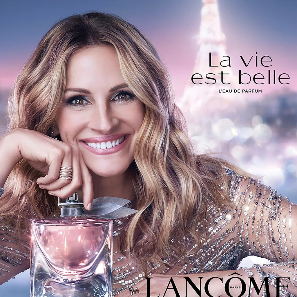 Lancome perfume advertisement with a woman holding a perfume bottle against a Parisian skyline.