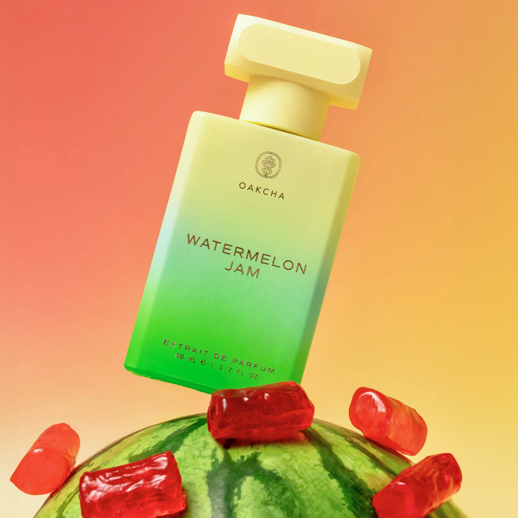 Perfume bottle labeled 'Watermelon Jam' on a watermelon with gummy bears against a gradient background