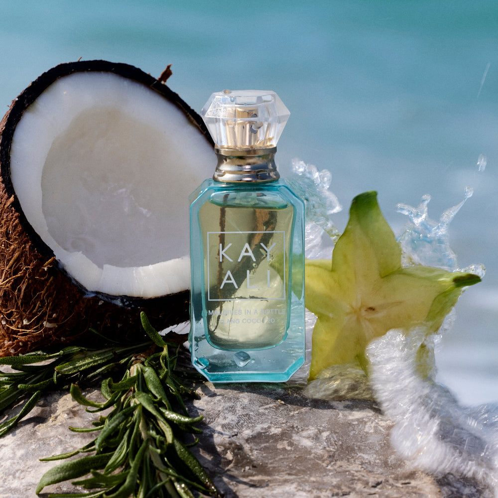 Perfume bottle with a star fruit and coconut on a beach background
