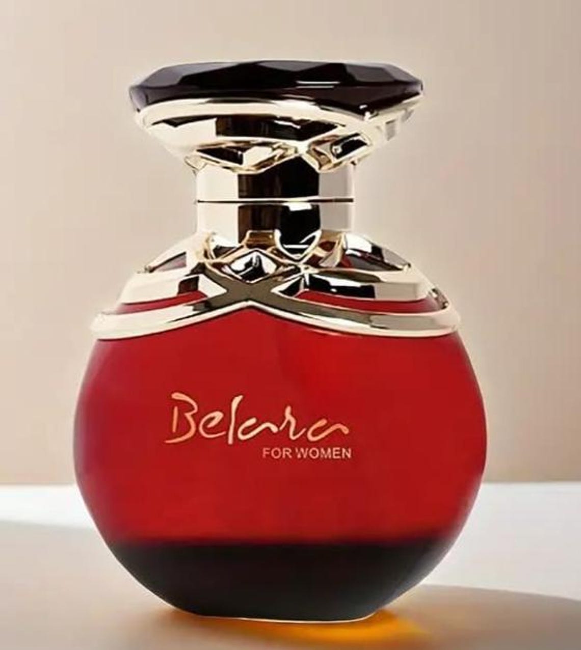 Red and gold perfume bottle with 'Belara' branding on a beige background