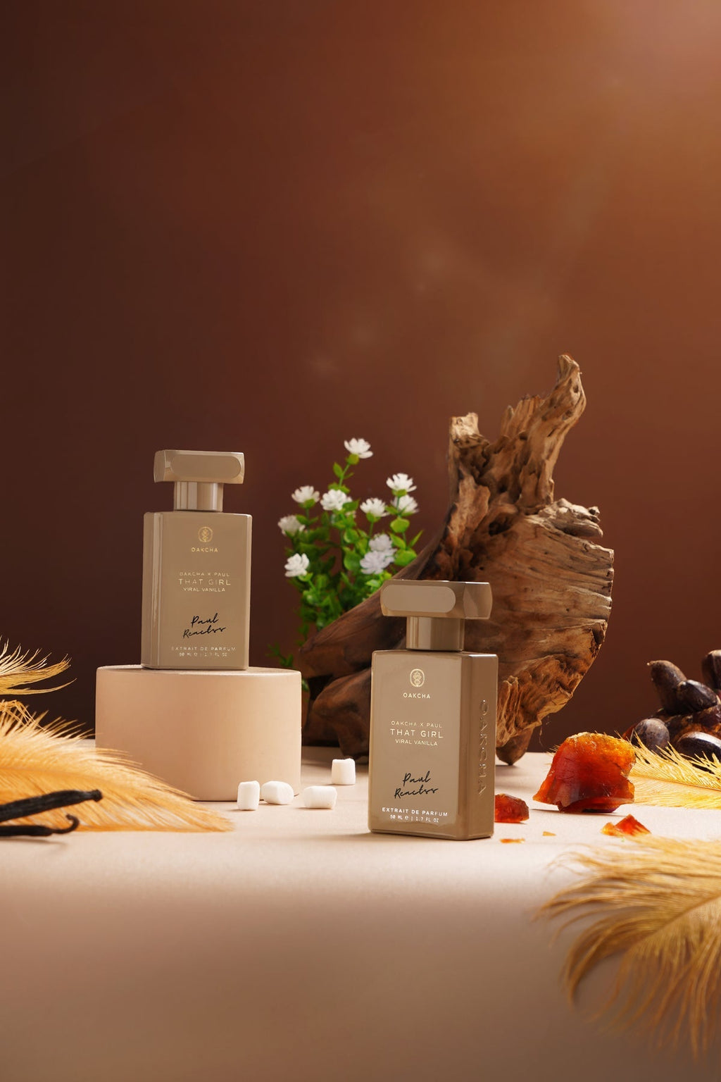 Two bottles of 'Fragrance' on a table with decorative elements against a brown background