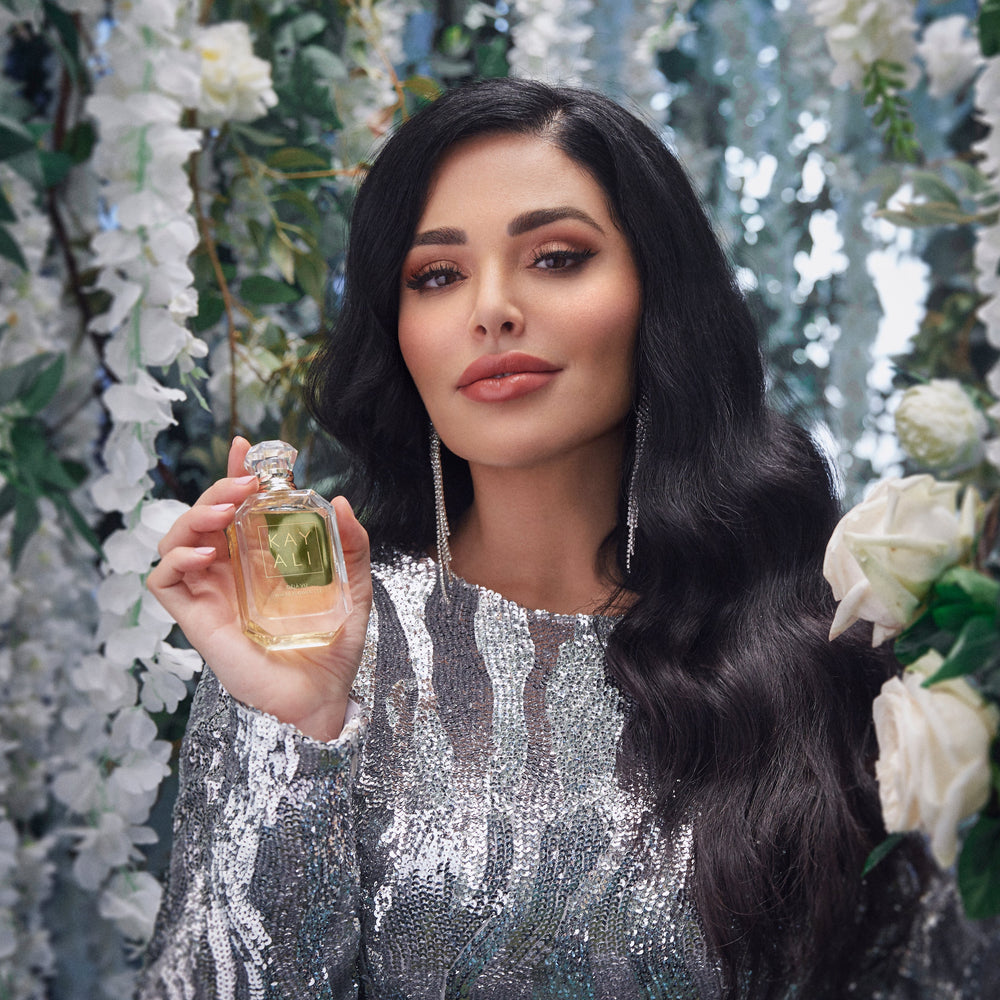 Woman holding a perfume bottle with floral and decorative background